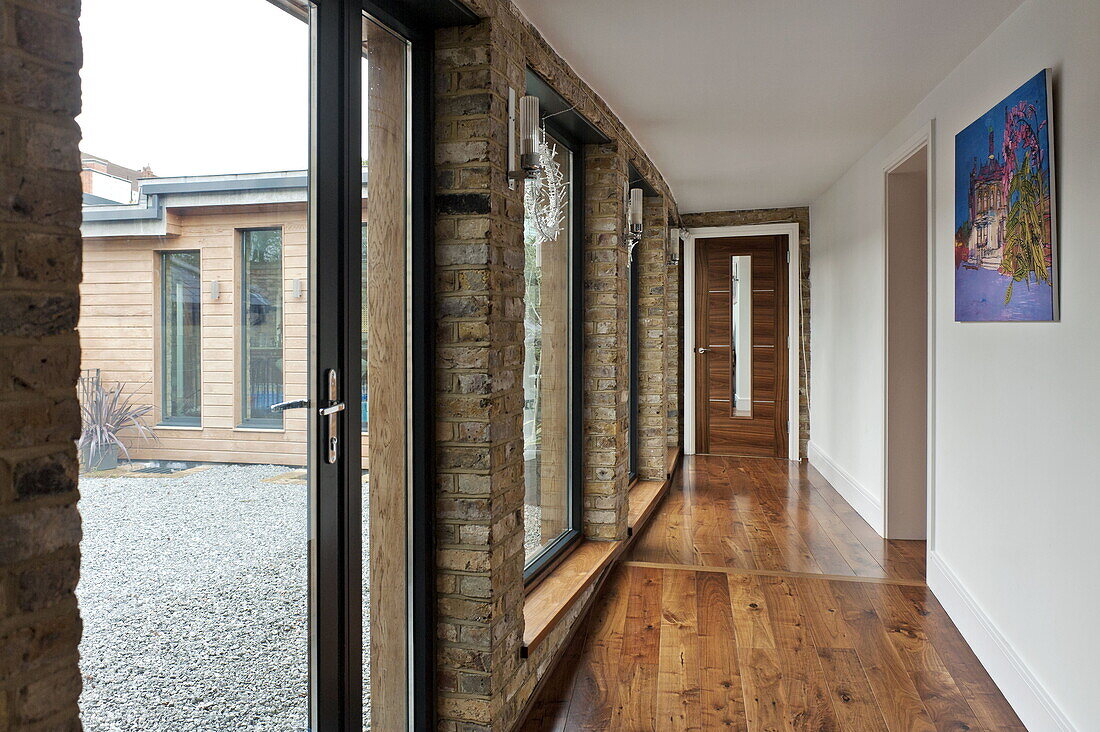 Wooden hallway with view through windows to gravel terrace in London home, England, UK