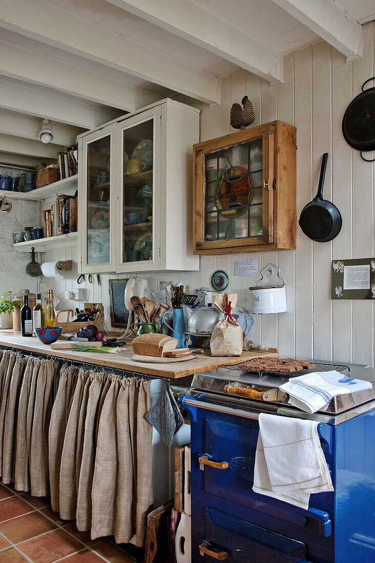 Wall mounted storage and blue oven in farmhouse kitchen, Cornwall, England, UK
