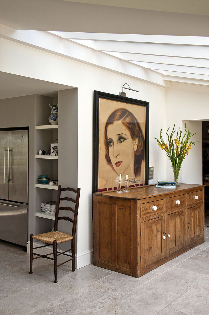 Wooden sideboard and artwork below skylight of conservatory in contemporary Suffolk country house, England, UK