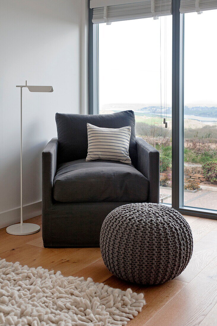 Dark grey armchair and pouf at window of Wadebridge home, Cornwall, England, UK
