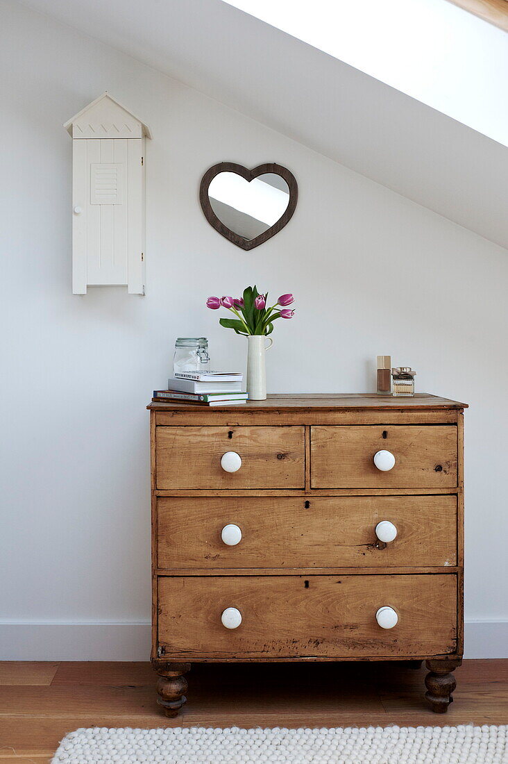 Holzkommode mit herzförmigem Spiegel im Schlafzimmer im Dachgeschoss eines Hauses in Wadebridge, Cornwall, England, UK