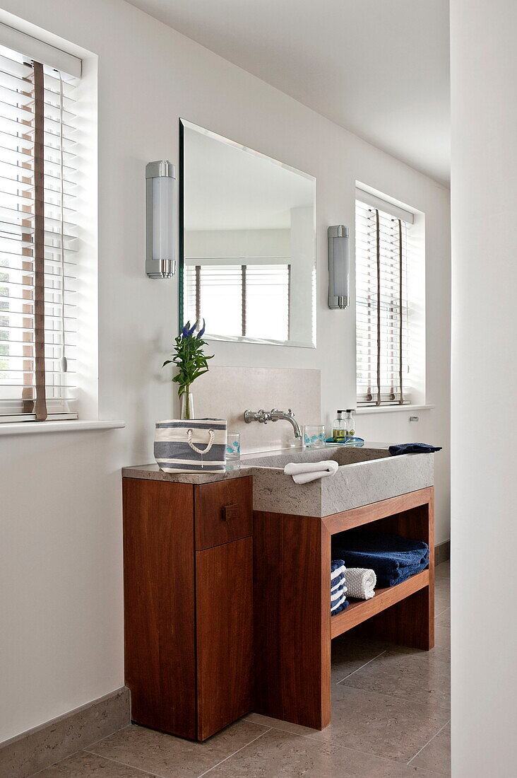 Wooden wash stand below mirror in bathroom of contemporary home, Cornwall, England, UK