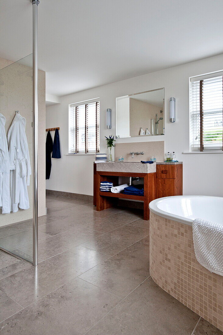 Bademäntel hängen in der geräumigen Nasszelle mit Duschabtrennung in einem modernen Haus, Cornwall, England, UK