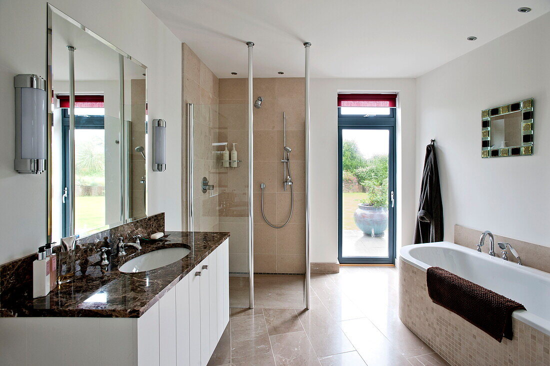 Badezimmer mit Duschkabine und Waschbeckeneinfassung aus braunem Marmor in einem modernen Haus, Cornwall, England, UK