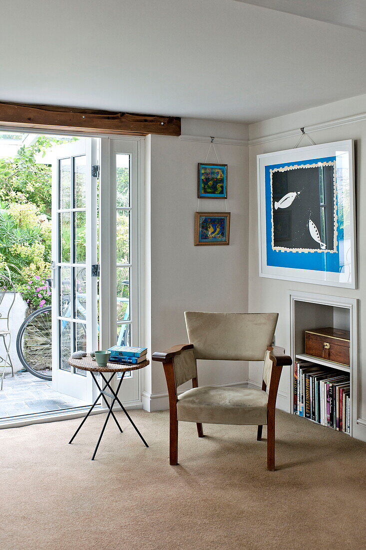 Vintage chair with artwork at open patio doors of Padstow cottage, Cornwall, England, UK