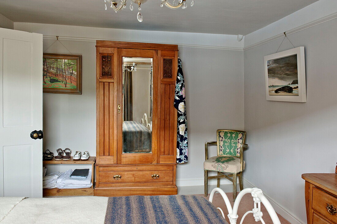 Antique wooden wardrobe and artwork in bedroom of Padstow cottage, Cornwall, England, UK