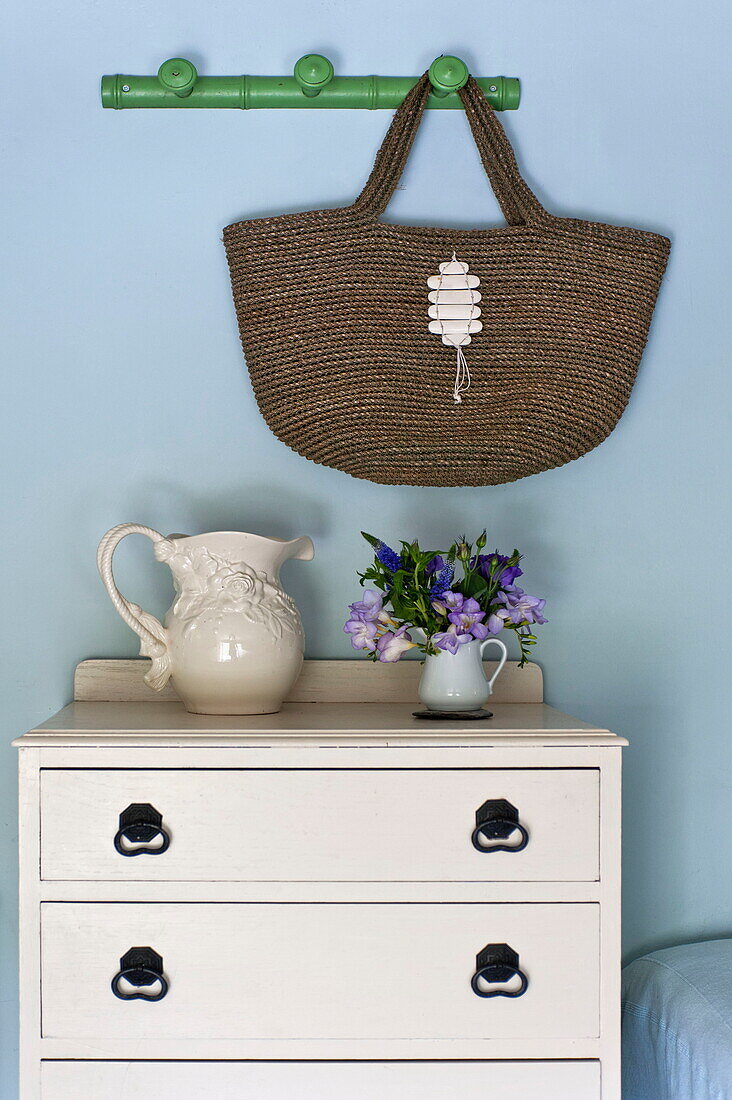 Einkaufstasche hängt über weiß gestrichenen Schubladen im Schlafzimmer eines Cottage in Padstow, Cornwall, England, UK
