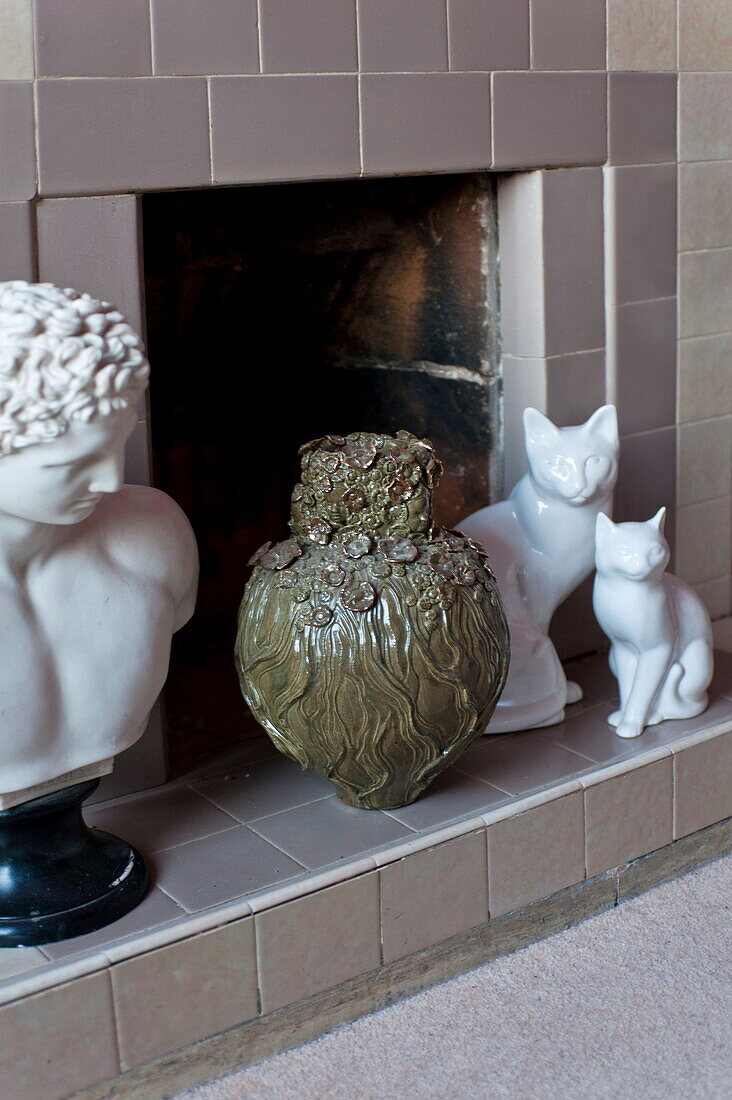 Keramikvase mit Katzen- und Büstenskulpturen im Kamin eines Hauses in London, England, UK