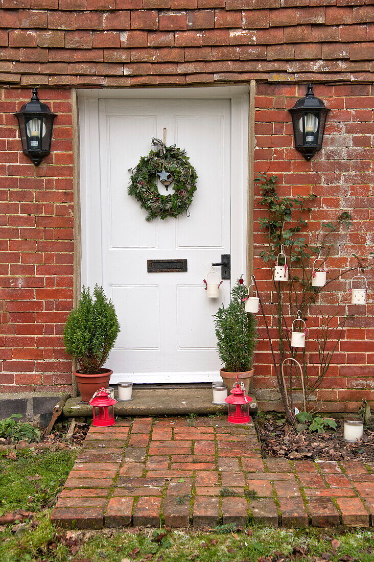 Floral wreath on front door of brick cottage, Shropshire, England, UK