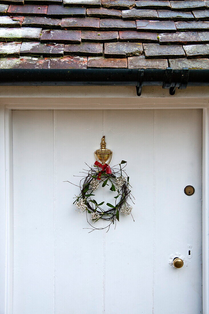 Floral wreath on white front door of Shropshire cottage, England, UK