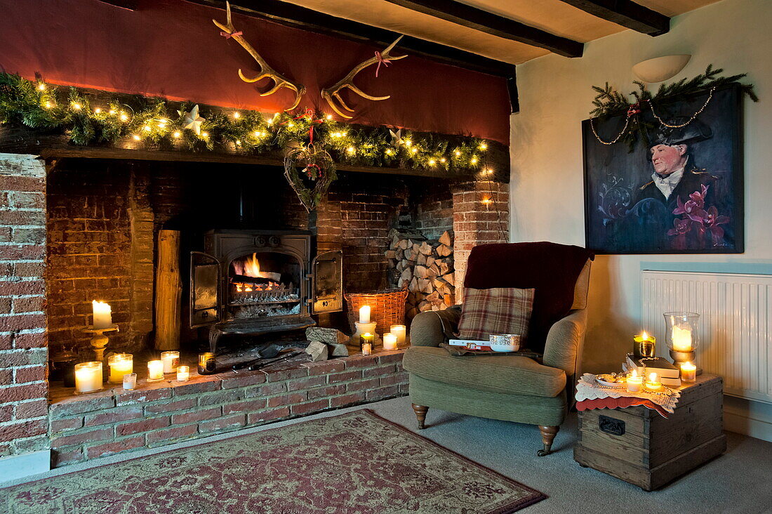 Fairylights and lit candles in exposed brick fireplace in Shropshire cottage, England, UK