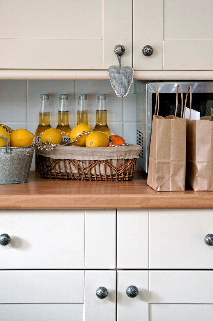Bierflaschen und Zitrusfrüchte auf der Arbeitsplatte in der Küche eines Cottage in Shropshire, England, Vereinigtes Königreich