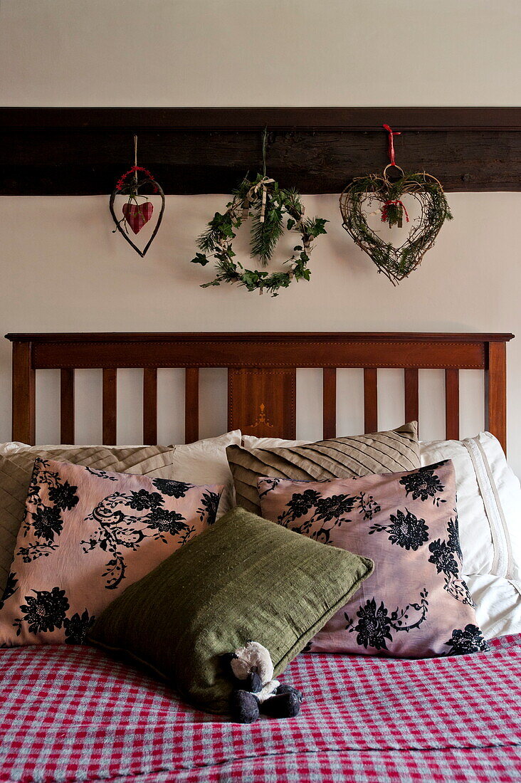 Christmas decorations hang above double bed with cushions in Shropshire cottage, England, UK