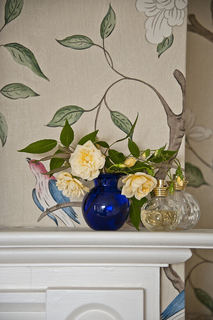 Gelbe Rosen in blauer Vase auf dem Kaminsims in einem modernen Landhaus in Suffolk, England, UK