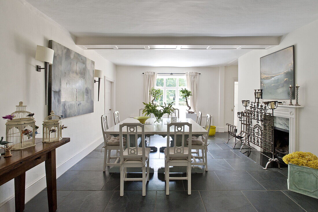 Weißer Esstisch und Stühle mit modernen Kunstwerken in einem modernen Haus in Suffolk/Essex, England, UK