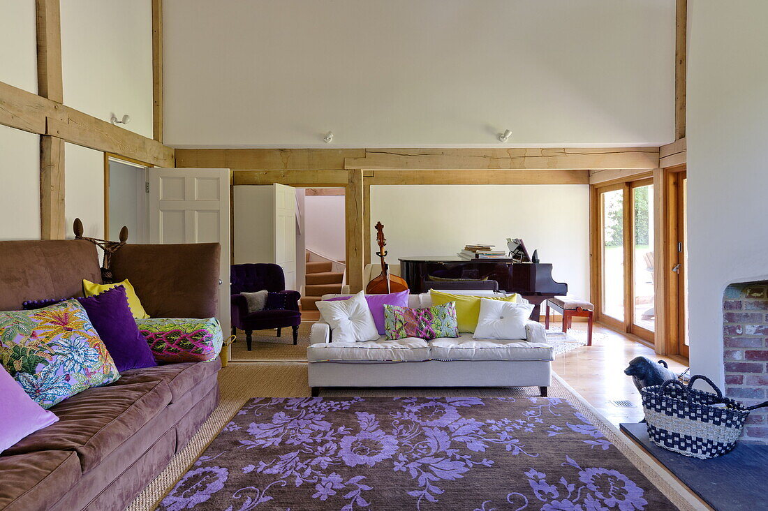 Kontrastierende Sofas mit blumengemustertem Teppich im offenen Wohnzimmer eines modernen Hauses in Suffolk/Essex, England, UK