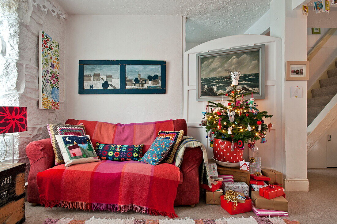 Crotchet-Kissen auf rotem Sofa mit Weihnachtsbaum in Penzance home Cornwall England UK
