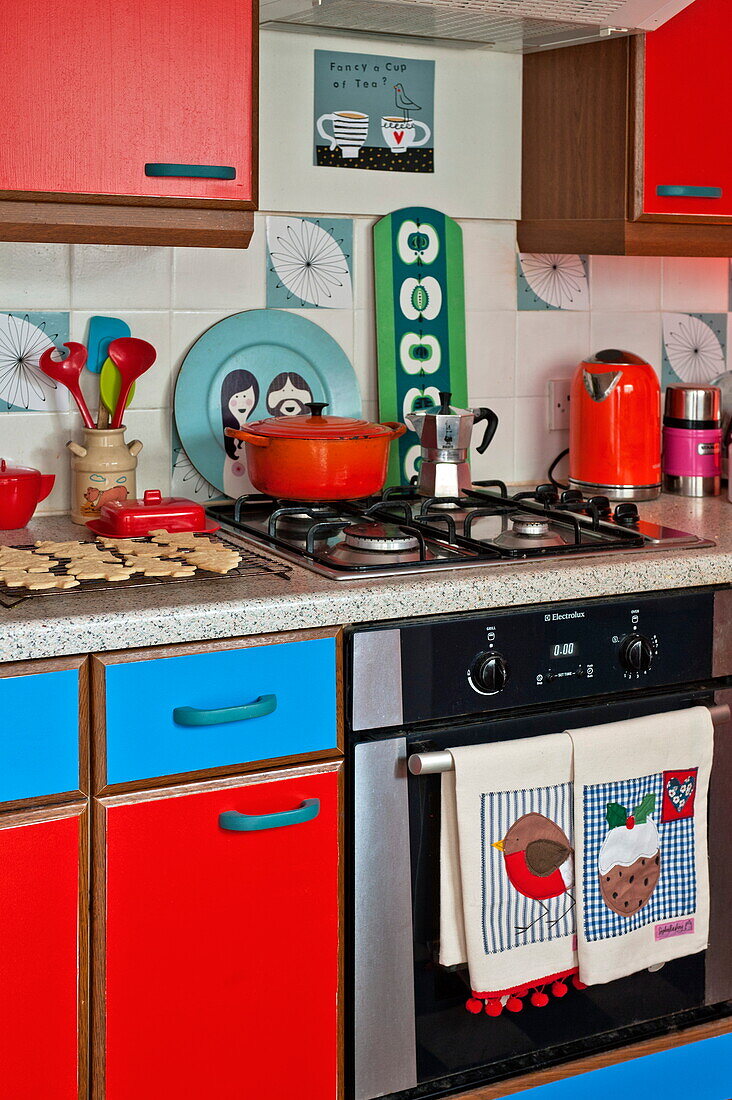 Red and blue fitted kitchen with baking on worktop in Penzance cottage Cornwall England UK