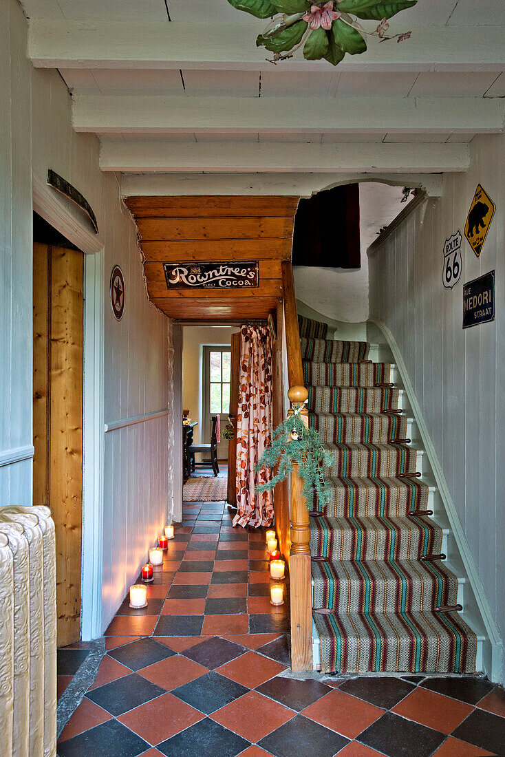 Lit candles in tiled hallway with carpeted stairs in Tregaron home Wales UK