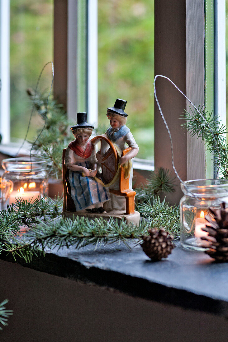 Spinning wheel figurines with pine cones and tealights on windowsill of Tregaron home Wales UK