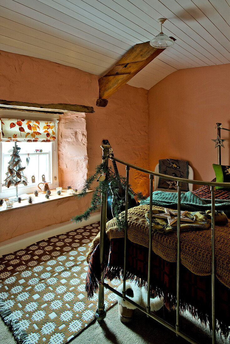 Trittbrett aus Messing mit Weihnachtsdekoration und gemustertem Teppich im pfirsichfarbenen Schlafzimmer des Hauses Tregaron in Wales (UK)