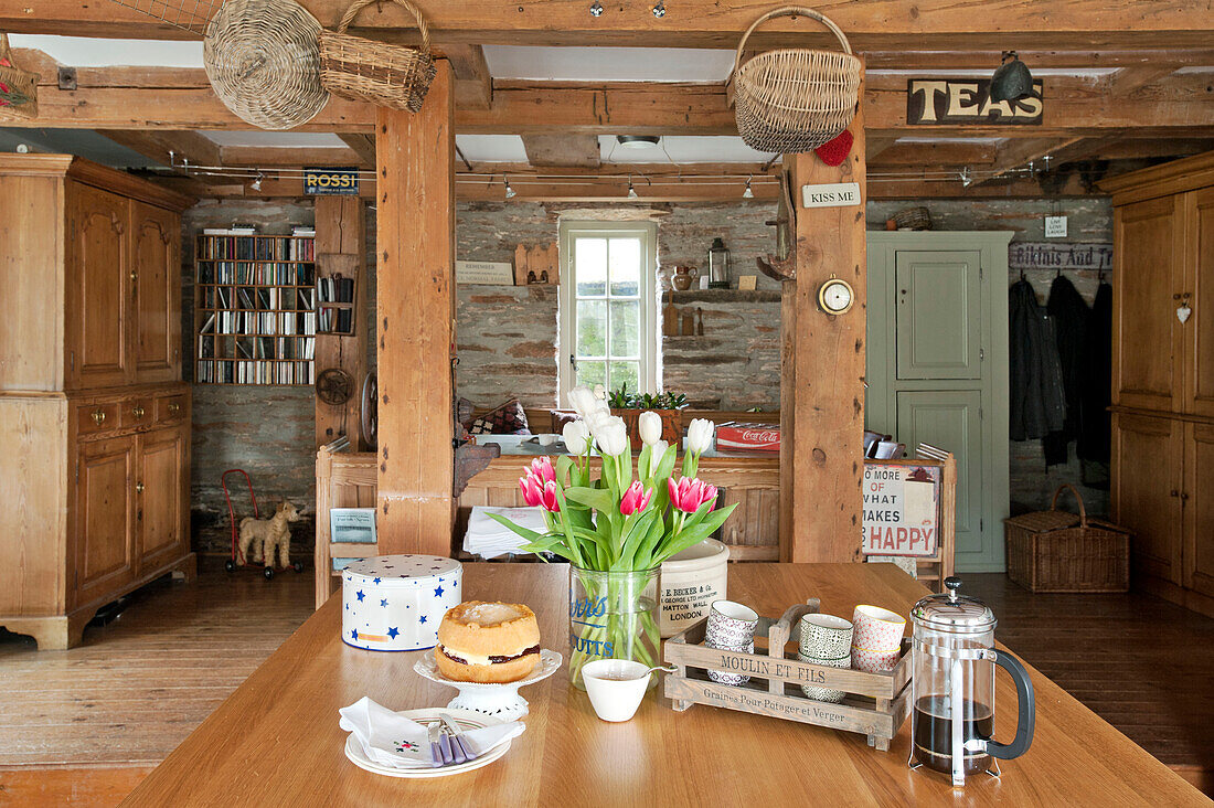 Geschnittene Tulpen und Tassen mit Biskuitkuchen auf einem Tisch in der offenen Küche einer umgebauten Scheune in Sherford, Devon UK