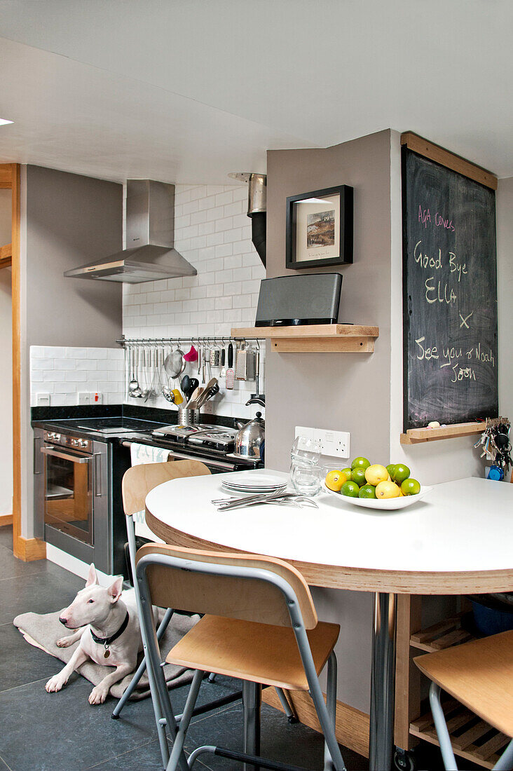 Folding chairs at table in modern kitchen with blackboard in Cornwall home UK