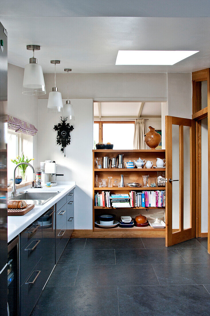 Open shelves with glass paned kitchen door in modern home, Cornwall, UK