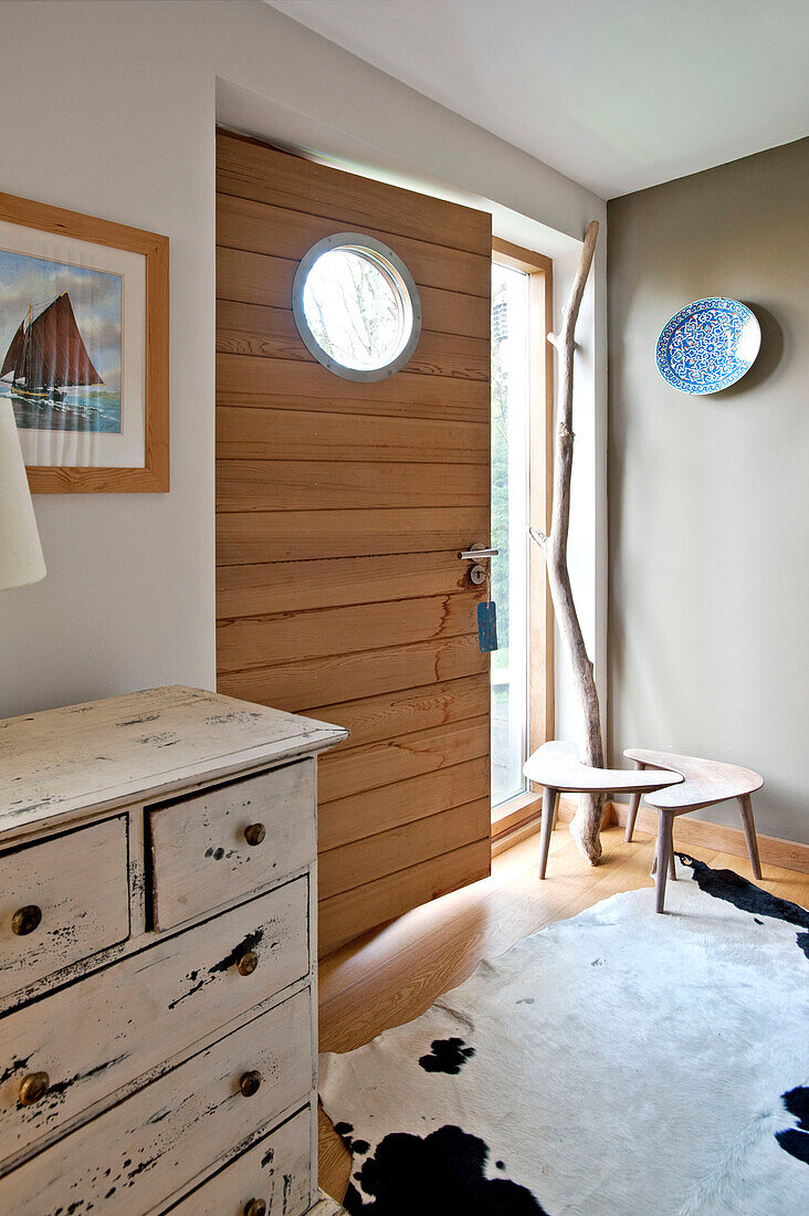 Cremefarbene Kommode und Holztür mit Bullauge im Haus in Cornwall UK
