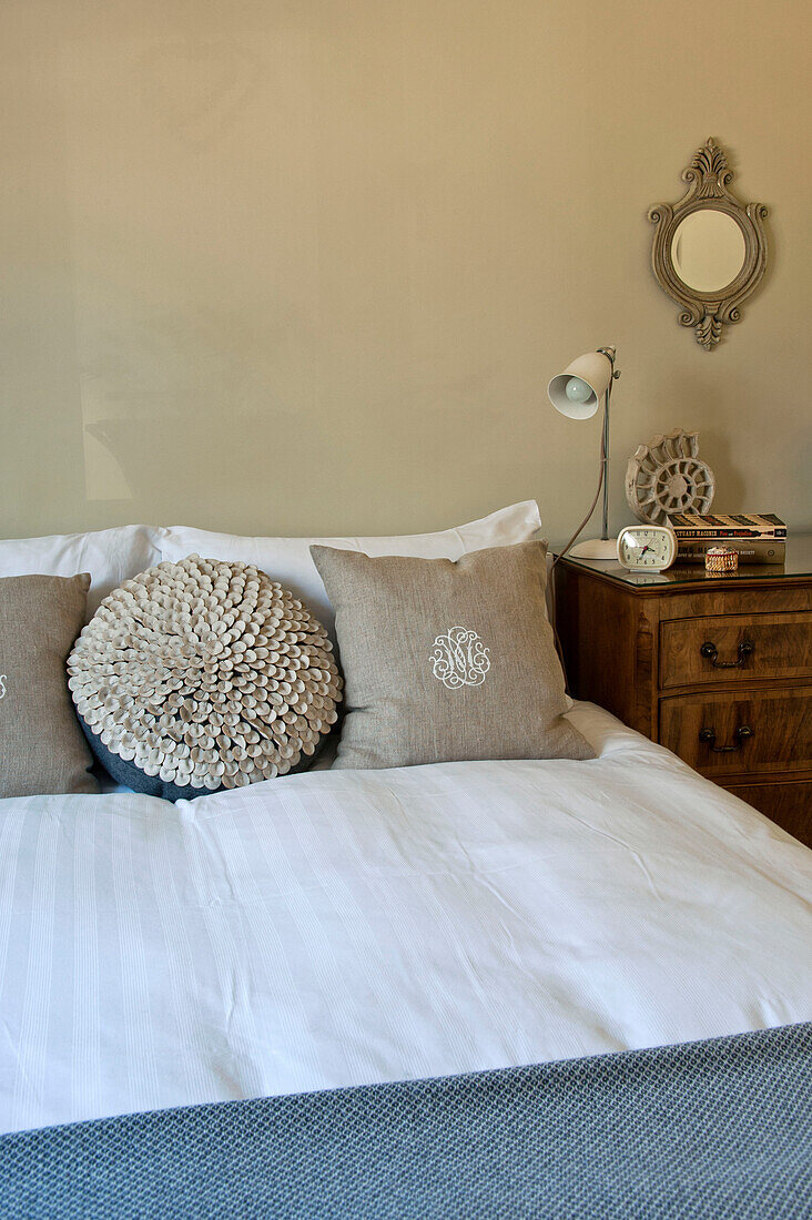 Square and circular linen cushions on double bed in family home, Cornwall, UK