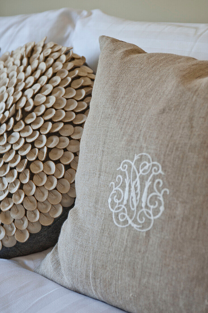 Monogram and textured cushions on bed in family home, Cornwall, UK