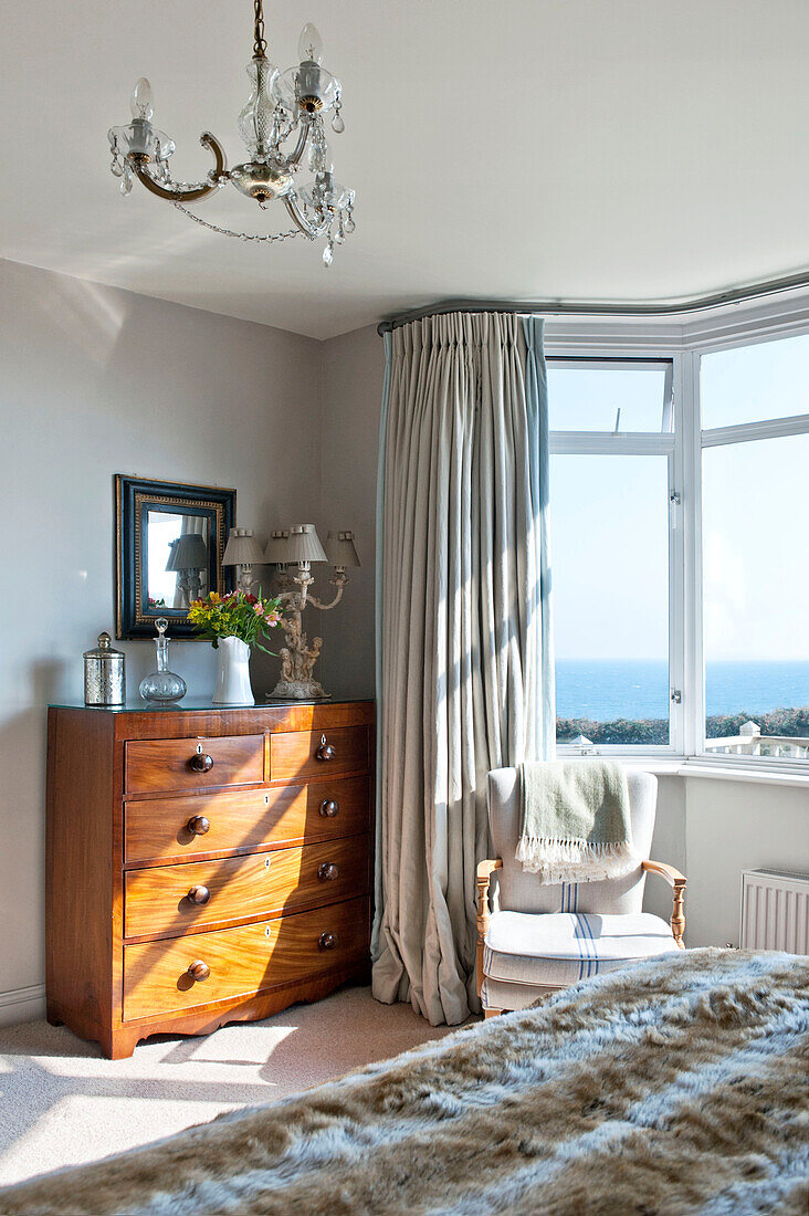 Von der Sonne beleuchtete Holzkommode am Erkerfenster im Schlafzimmer eines Einfamilienhauses, Cornwall, Vereinigtes Königreich