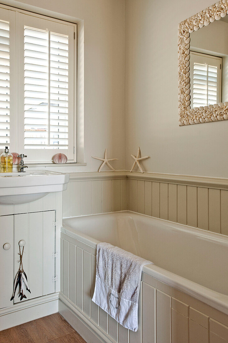 Cream bathroom with shutters in family home Cornwall UK