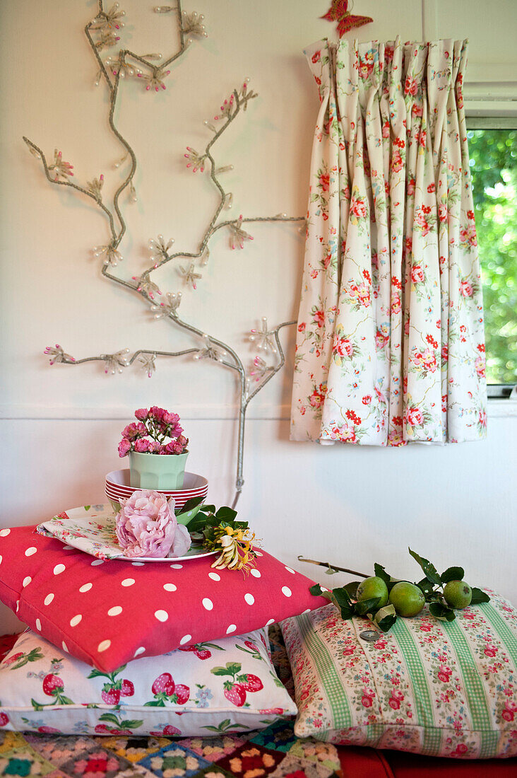Helle Dekoration und verschiedene Kissen mit floral gemusterten Vorhängen im Wohnwagen