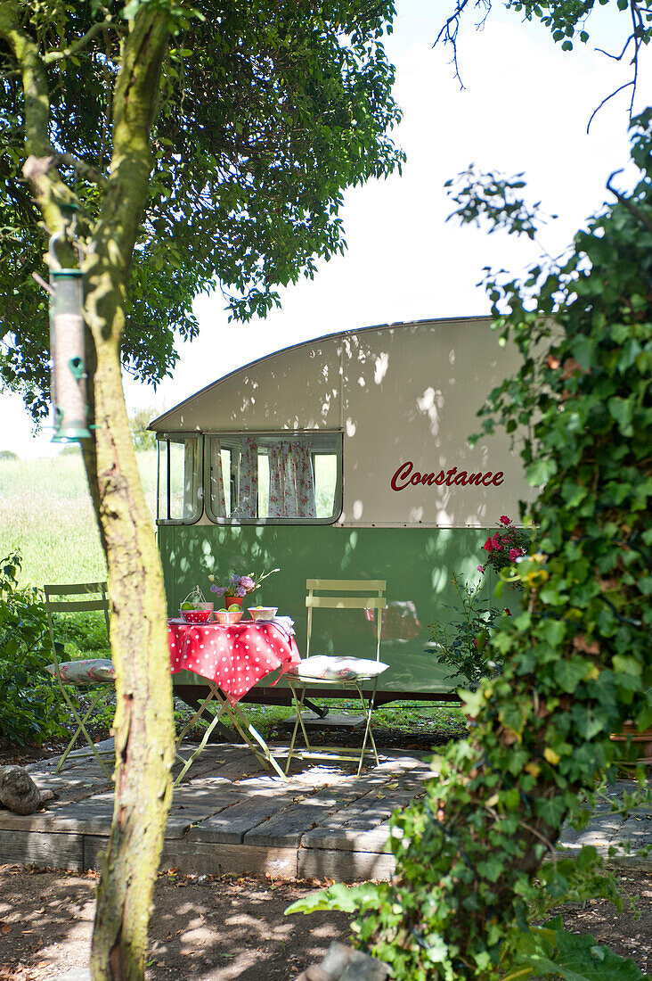 Klappstühle und Tisch auf einer schattigen Wohnwagen-Terrasse