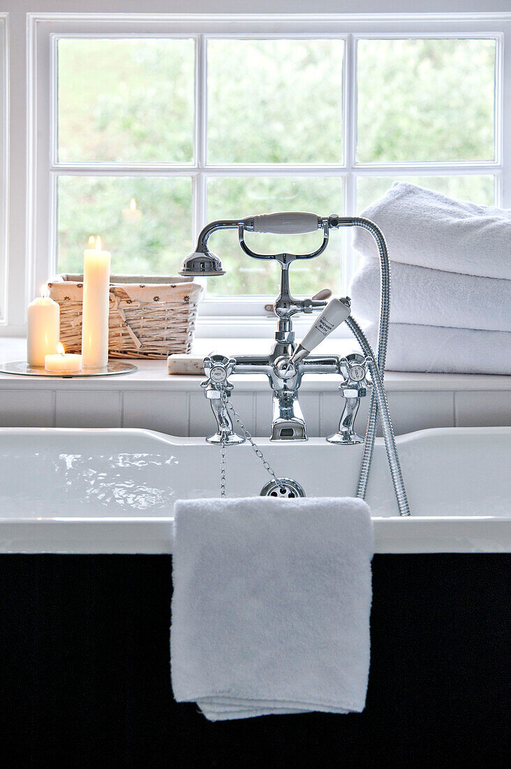 Chrome shower fitting on freestanding bath at window of Crantock home Cornwall England UK