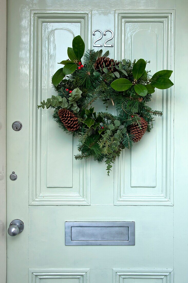 Floraler Weihnachtskranz an pastellgrüner Eingangstür in einem Haus in Penzance, England UK