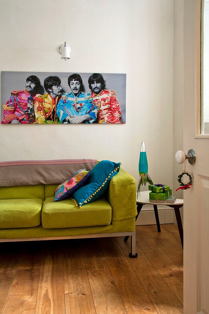 Beatles-Kunstwerk über lindgrünem Sofa im Wohnzimmer eines Familienhauses in Penzance, Cornwall, England, UK