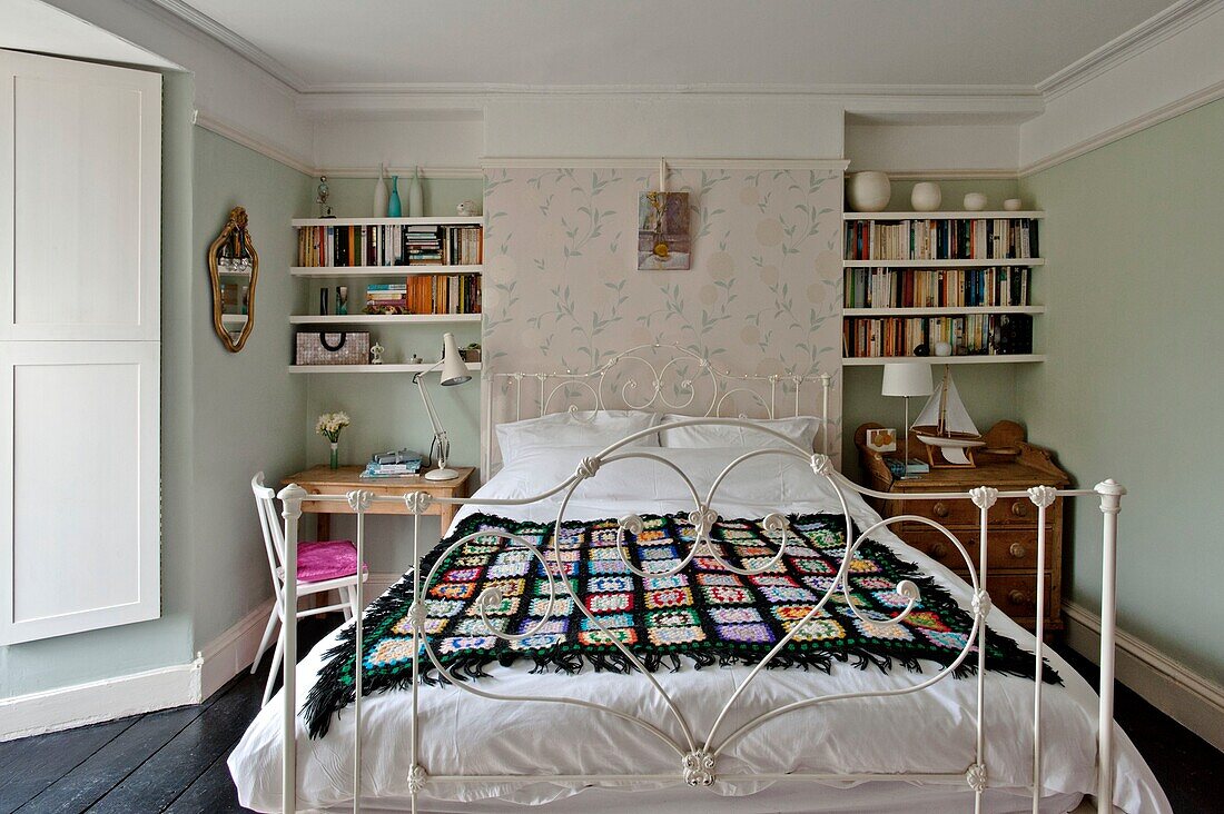 Schwarze Häkeldecke auf einem Doppelbett mit Bücherregal in einem Einfamilienhaus in Penzance Cornwall England UK