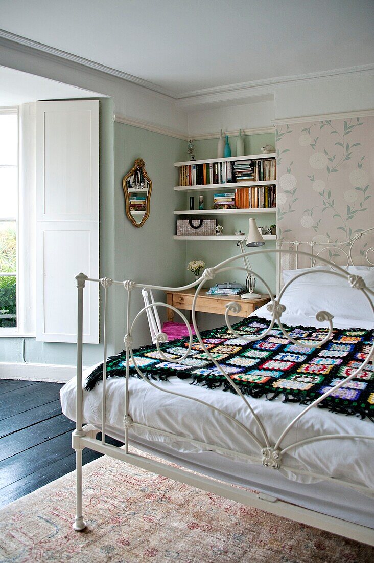 Schwarze Häkeldecke auf einem Doppelbett mit Bücherregal in einem Einfamilienhaus in Penzance, Cornwall, England, UK