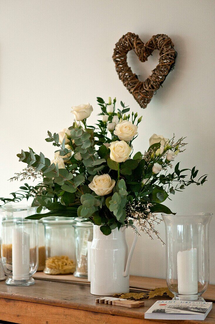 Weiße Rosen und Glaskerzen mit herzförmigem Kranz im Haus der Familie in Wadebridge, North Cornwall, UK