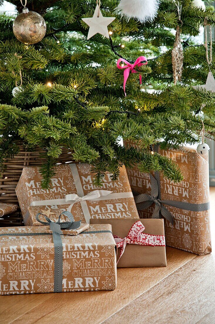 Gift wrapped presents under Christmas tree in Wadebridge home, North Cornwall, UK