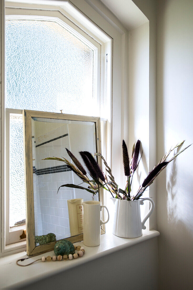 Getrocknete Gräser in Keramikkrug mit Spiegel auf Fensterbank in Stamford home Lincolnshire England UK