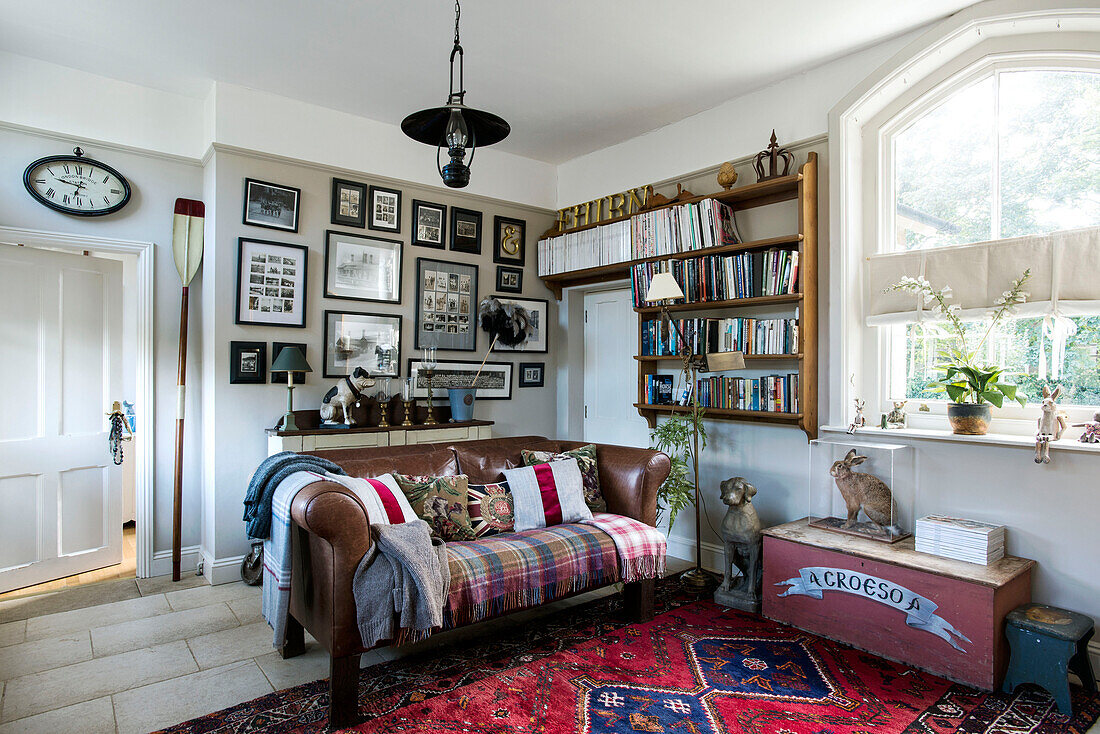 Regale und gerahmte Drucke über einem braunen Ledersofa im Wohnzimmer eines Hauses in Stamford, Lincolnshire, England, UK