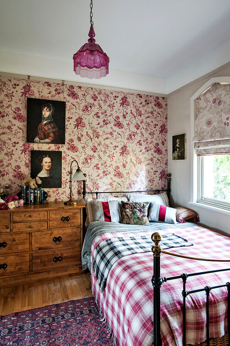 Artwork portraits on floral wallpaper above single bed in Stamford home Lincolnshire England UK