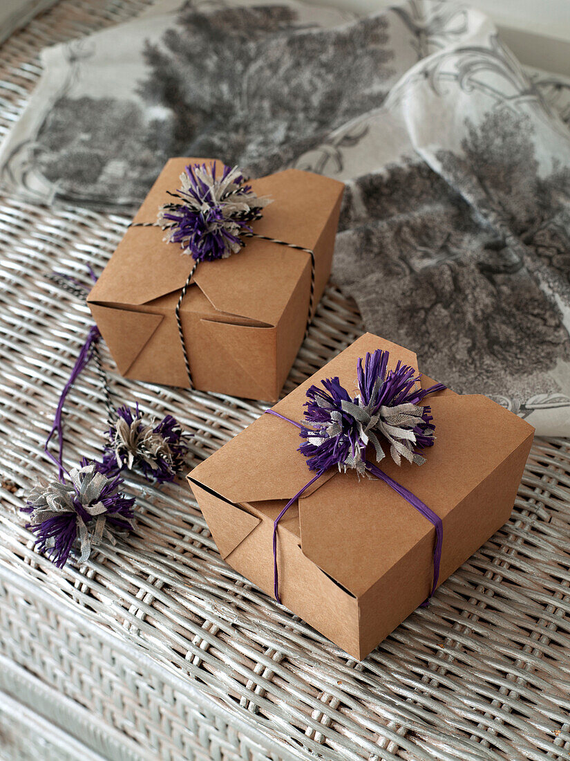 Cardboard gift boxes tied with purple bows on wicker basket London England UK