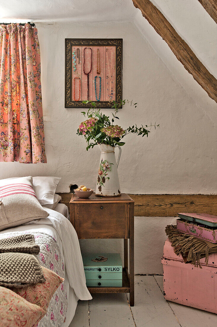 Cut flowers on wooden bedside table in Cambridge cottage England UK
