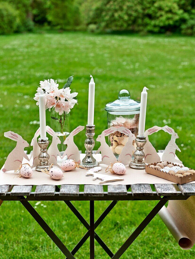 Easter rabbits and silver candlesticks with cut flowers on Sussex garden table England UK