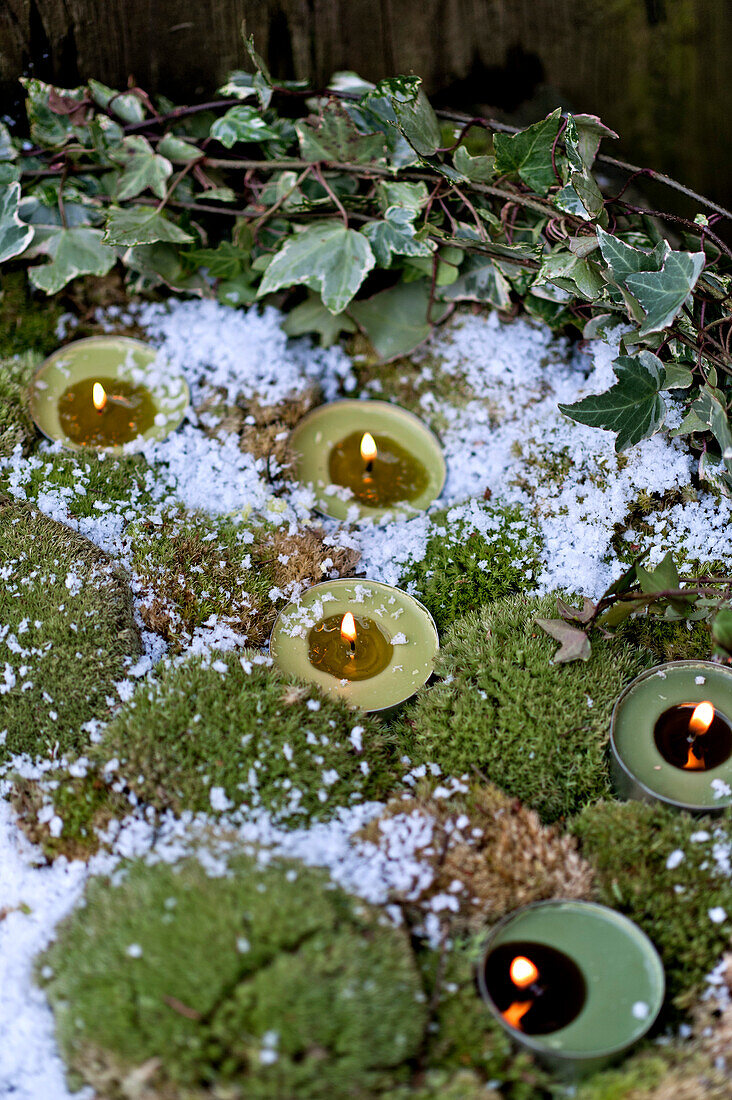 Lit tealights and moss with ivy in London garden England UK
