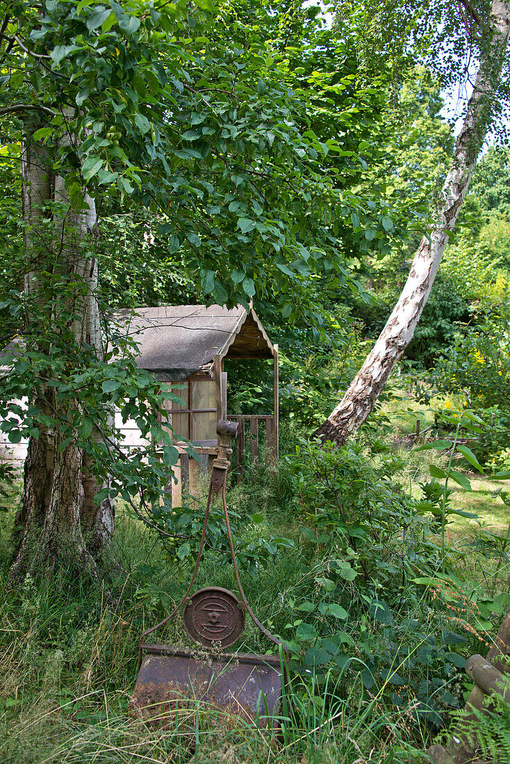 Hölzernes Gartenhaus mit alter Walze in East Grinstead Garten Sussex England UK